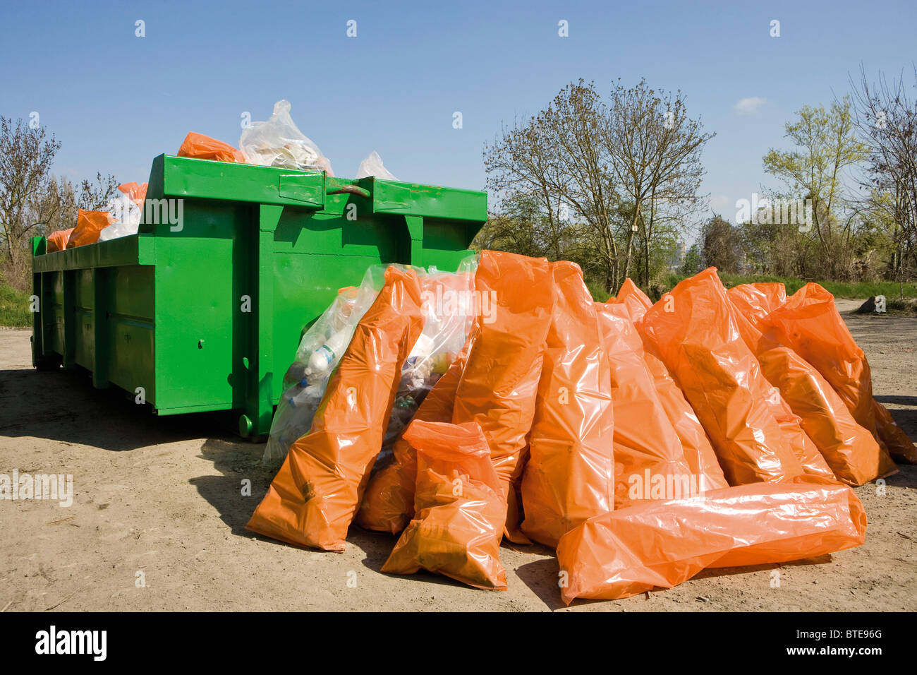 Müllsäcke gestapelt neben Müllcontainer Stockfoto