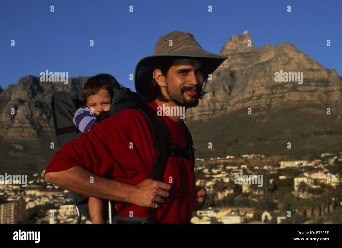 Ein bärtiger Mann mit Hut Wandern mit seinem Sohn in einem Träger von Camps Bay, Tafelberg (Modell freigegeben) Stockfoto
