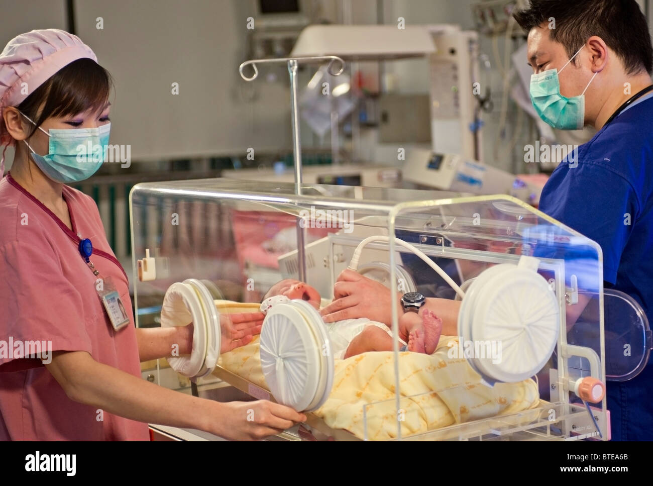 Arzt und Krankenschwester untersuchen neugeborenes Baby im Inkubator Stockfoto