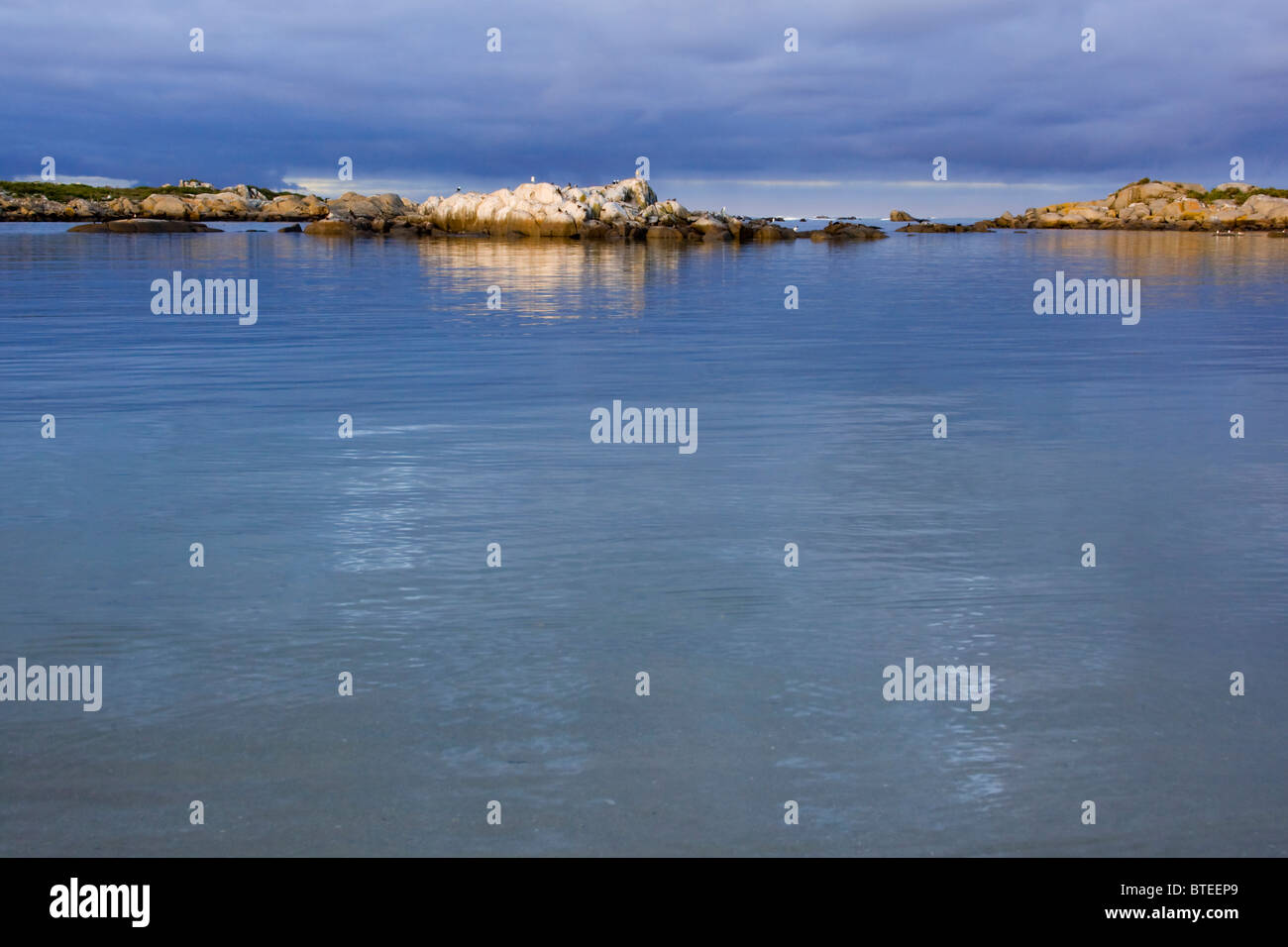 Blaues Wasser und ein blauer Himmel mit Inseln der Felsen im Hintergrund Stockfoto