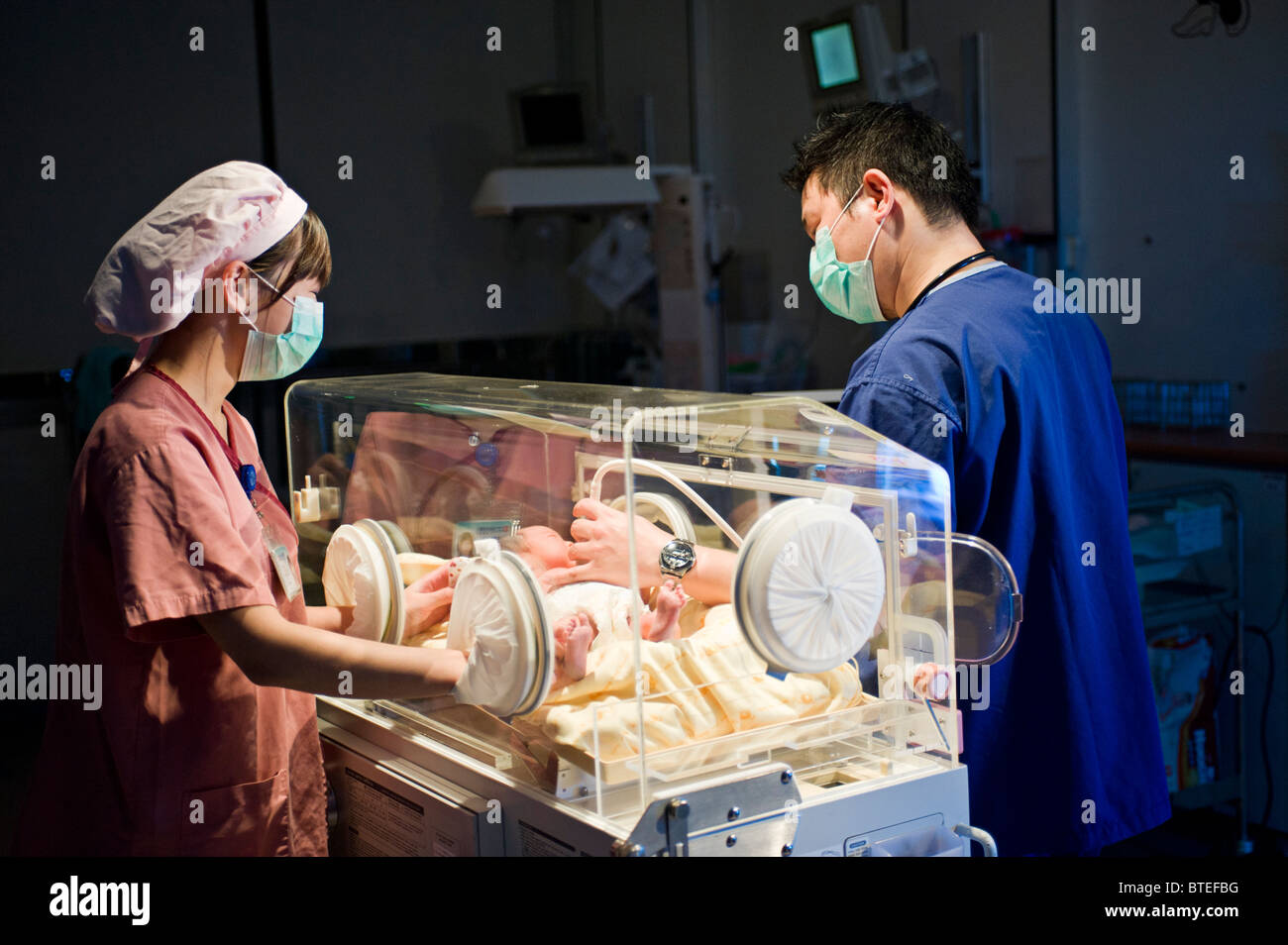 Arzt und Krankenschwester untersuchen neugeborenes Baby im Inkubator Stockfoto