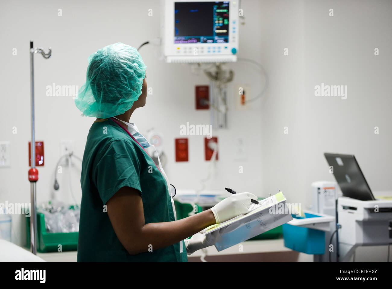 Krankenschwester Überprüfung medizinischer Geräte Monitor, Datenaufzeichnung in medizinischen Diagramm Stockfoto