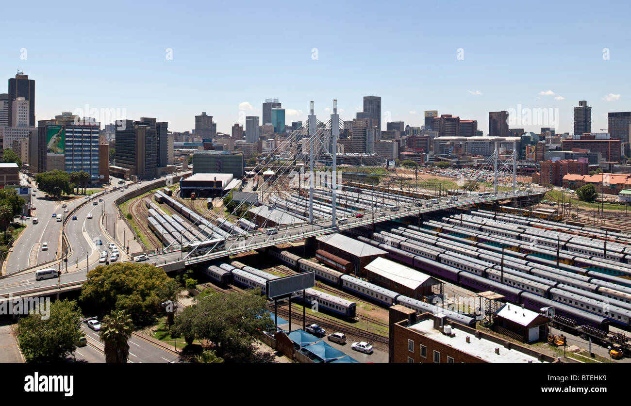 Der Nelson-Mandela-Brücke über die Park Street Railway Station mit der Johannesburg Skyline im Hintergrund Stockfoto