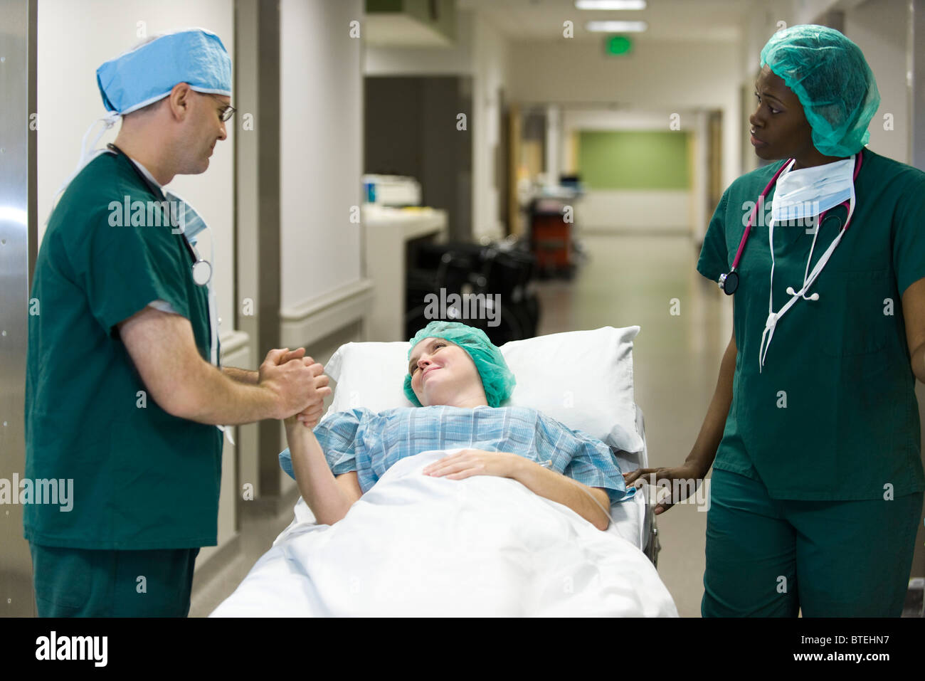 Arzt am Krankenhaus Gurney beruhigend Patienten liegen Stockfoto