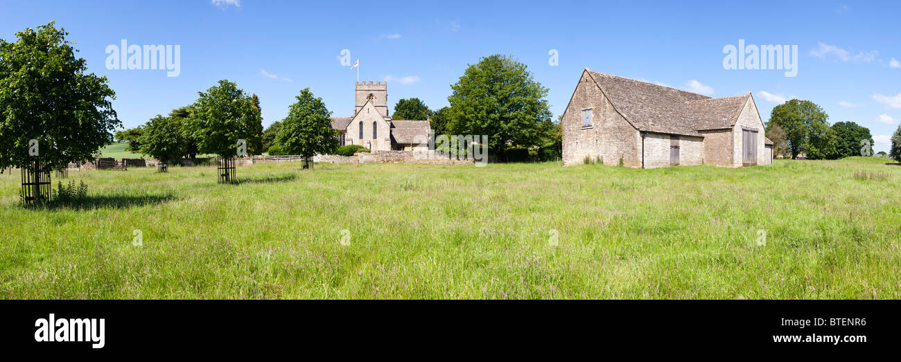 Einen Panoramablick über Norman St. Michaelis-Kirche und eine Scheune in der Cotswold Dorf Guiting Power, Gloucestershire Stockfoto
