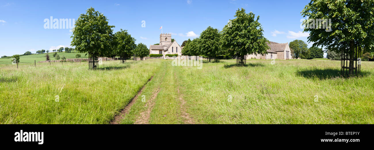 Einen Panoramablick über Norman St. Michaelis-Kirche und eine Scheune in der Cotswold Dorf Guiting Power, Gloucestershire Stockfoto