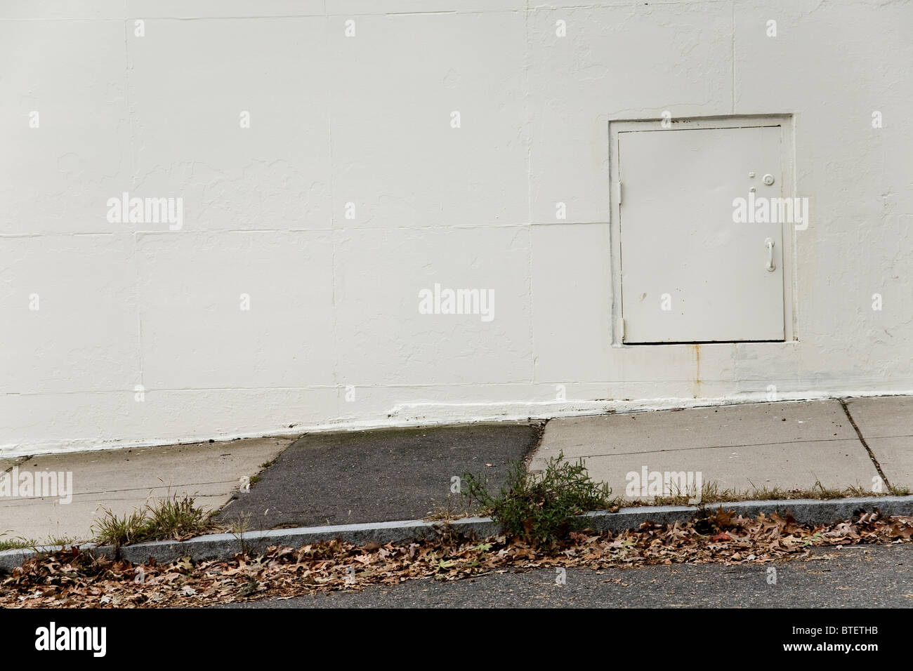 Kleine verschlossene Tür an der Außenwand eines Gebäudes Stockfoto