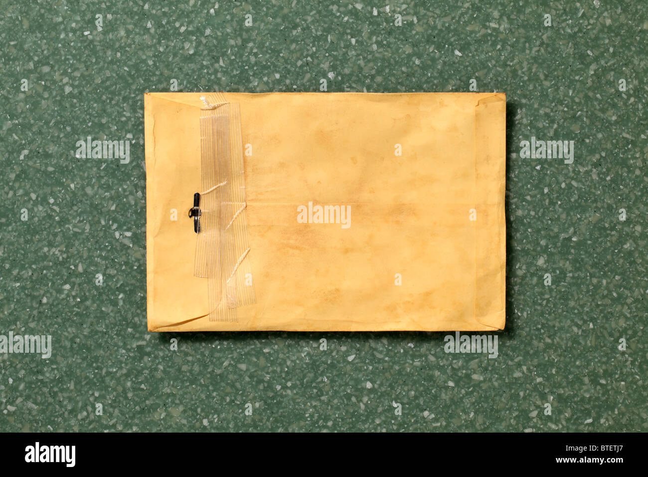 Eine gebrauchte mailing Postumschlag aufgerissen. Grün gesprenkelt Counter Top Hintergrund Stockfoto