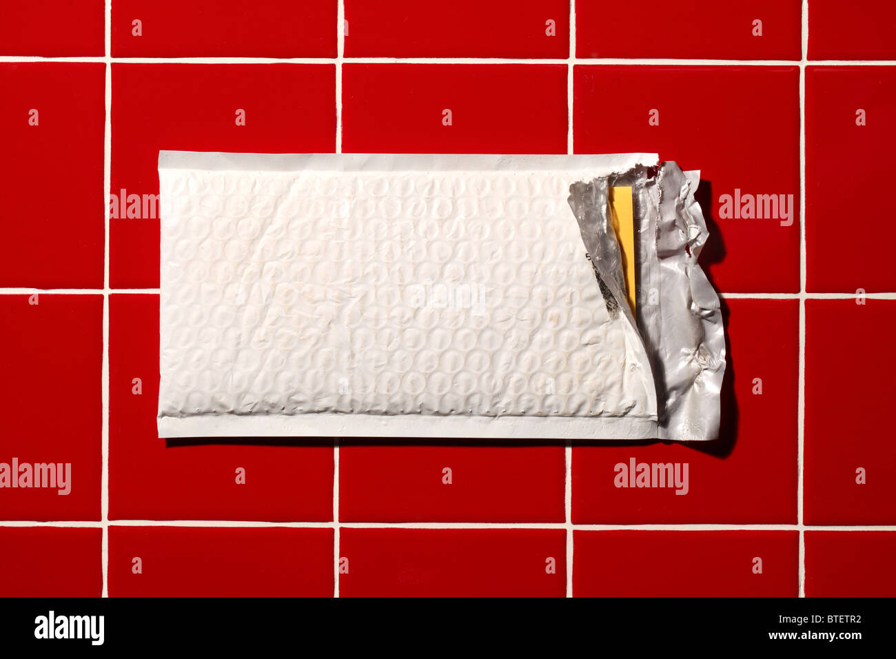 Eine gebrauchte mailing Postumschlag aufgerissen. Rot gekachelter Hintergrund Stockfoto