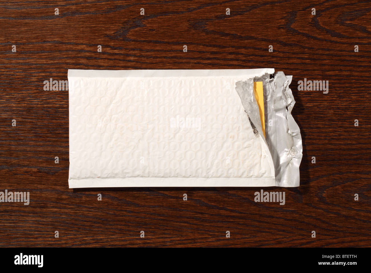 Eine gebrauchte mailing Postumschlag aufgerissen. Eine dunkle braune Holz Schreibtisch-Hintergrund Stockfoto