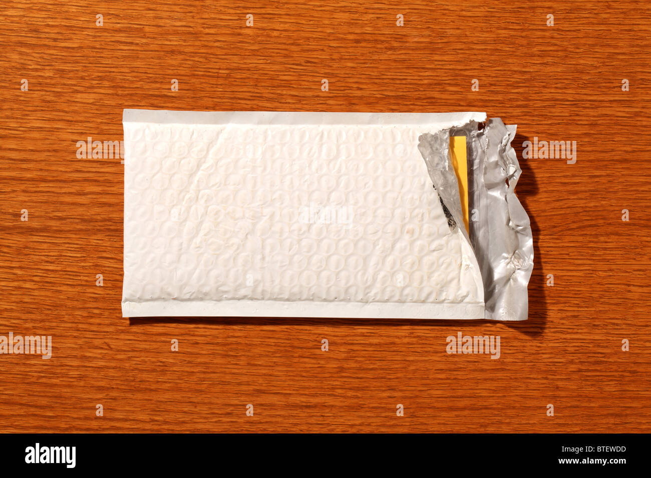 Eine gebrauchte mailing Postumschlag aufgerissen. Braune Holz gemaserte Hintergrund Stockfoto