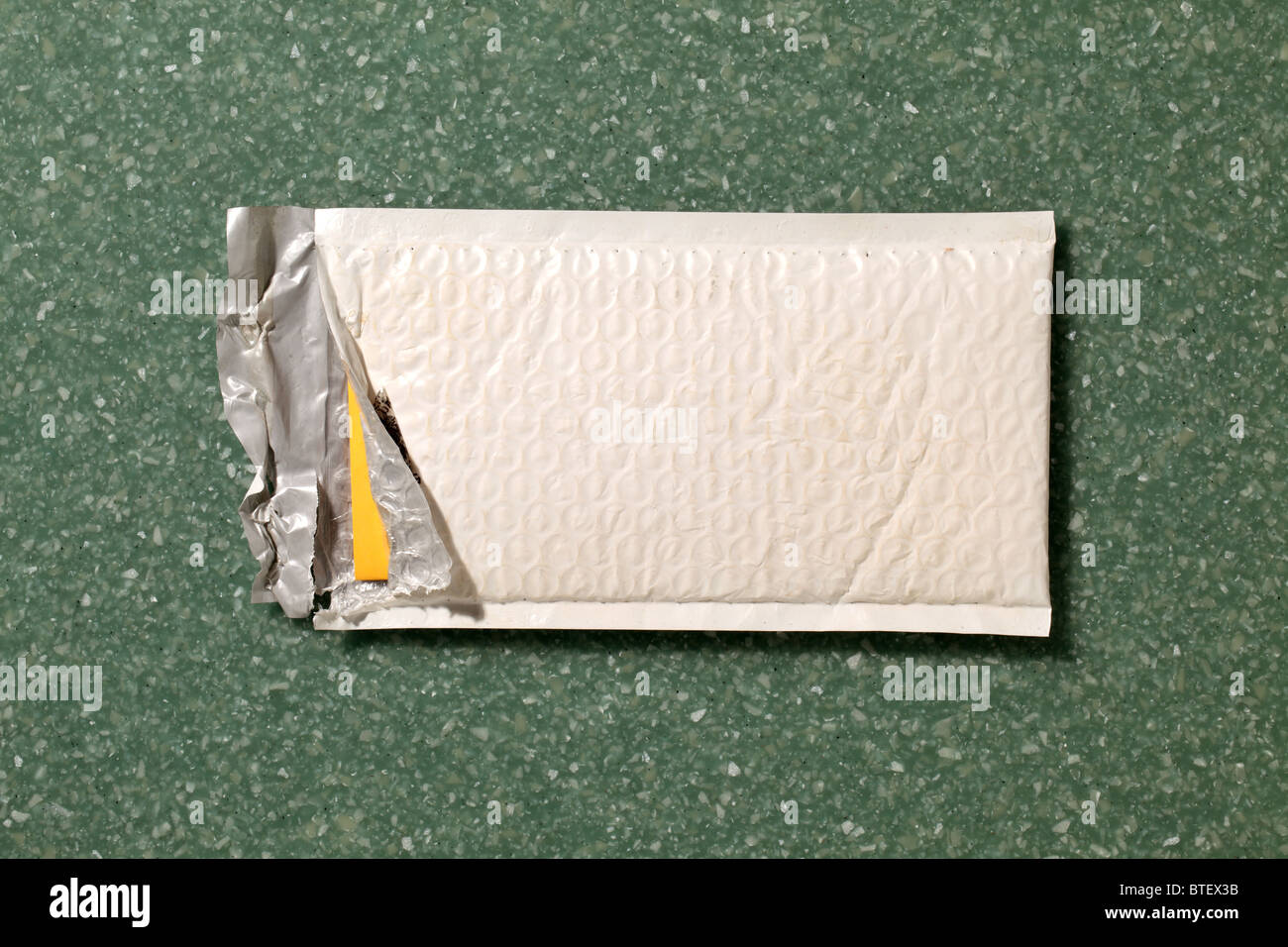 Eine gebrauchte mailing Postumschlag aufgerissen. Grün gesprenkelt Counter Top Hintergrund Stockfoto