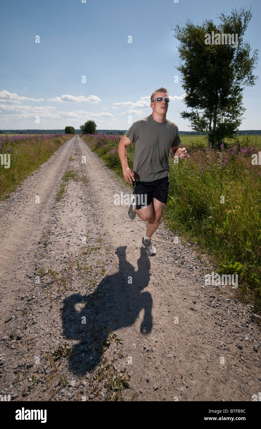 Sportlichen Mann läuft auf Feldweg an heißen Sommertag. Stockfoto