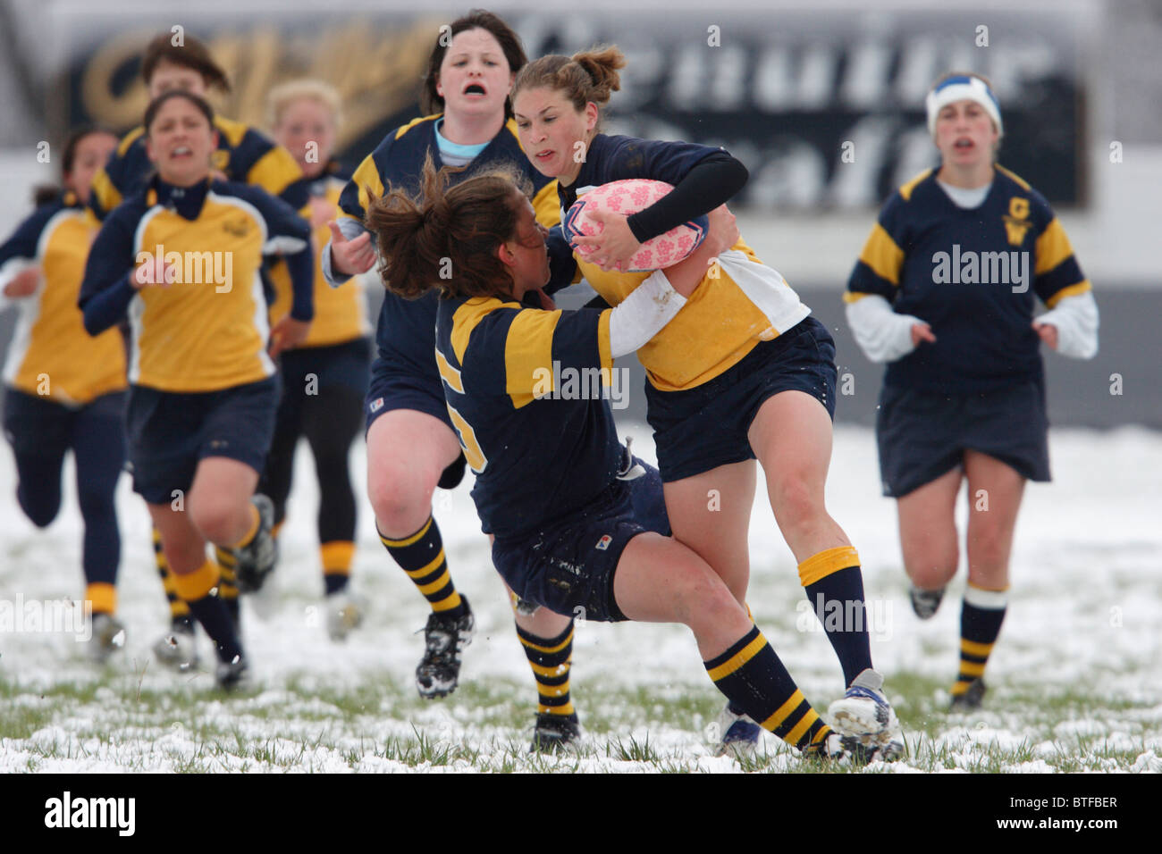 Eine Marineakademie Ballträger kollidiert mit einem George Washington University-Gegner während einer verschneiten Frauen Rugby-Spiel. Stockfoto