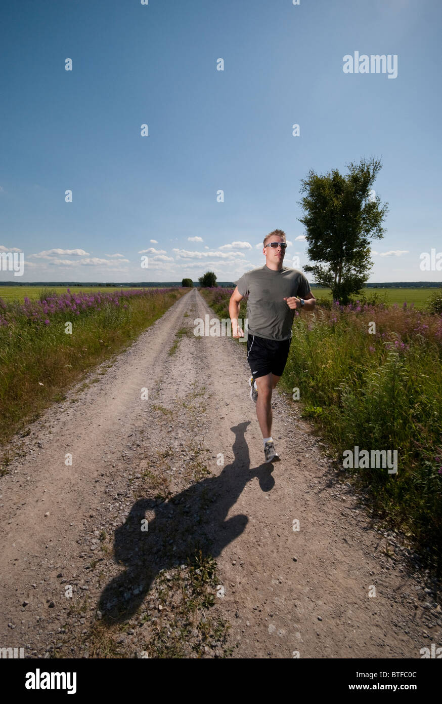 Sportlichen Mann läuft auf Feldweg an heißen Sommertag. Stockfoto