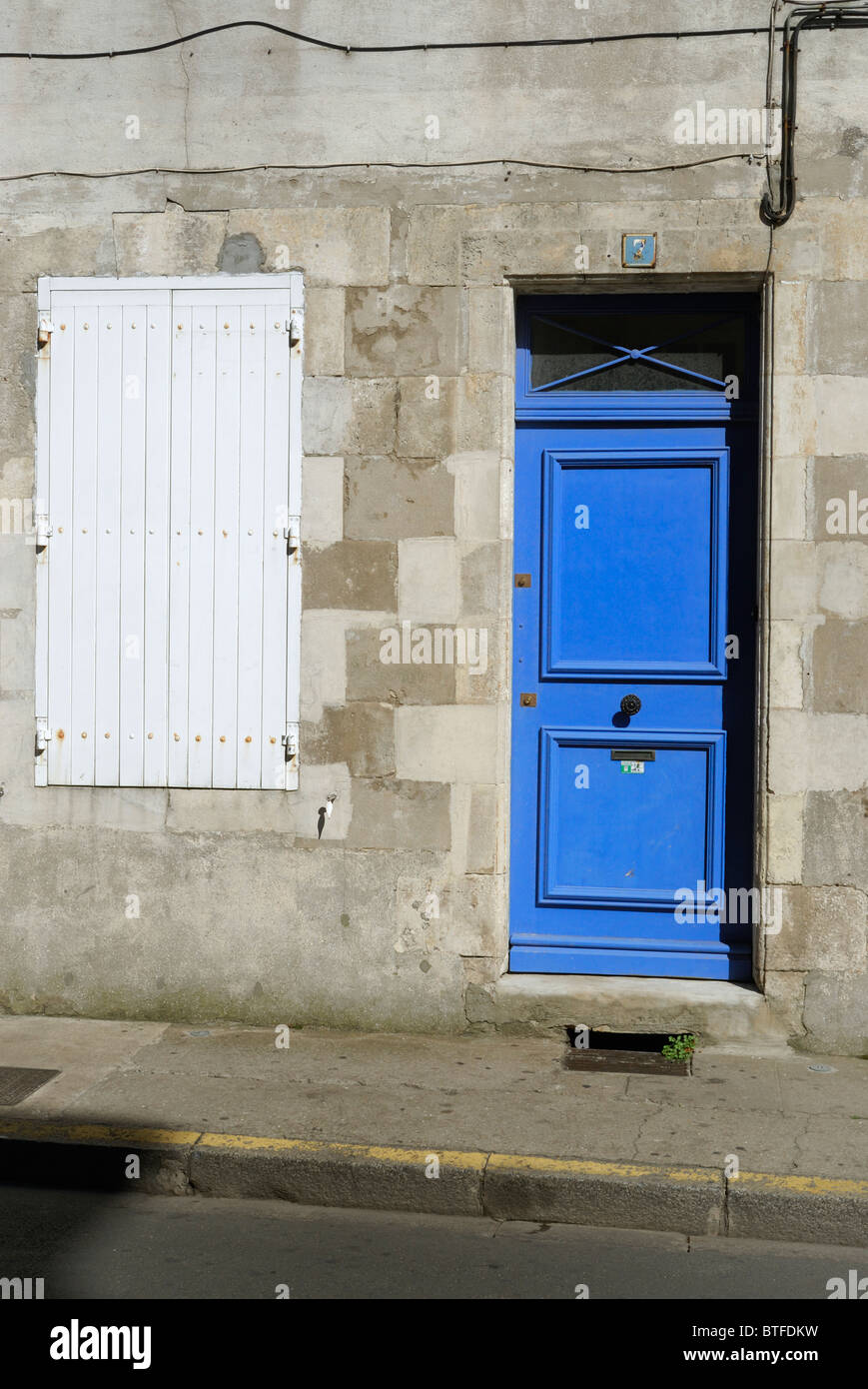 Eine geschlossenen blau bemalte Tür zu einem Haus neben einem Fenster mit seinen weißen Fensterläden geschlossen, Paris Frankreich. Stockfoto