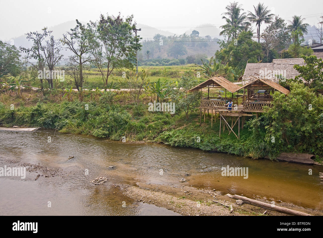 Frau steht auf einer Terrasse vor ihrem Haus entlang des Mae Taeng River in Chiang Mai-Bereich von Nord-Thailand. Stockfoto