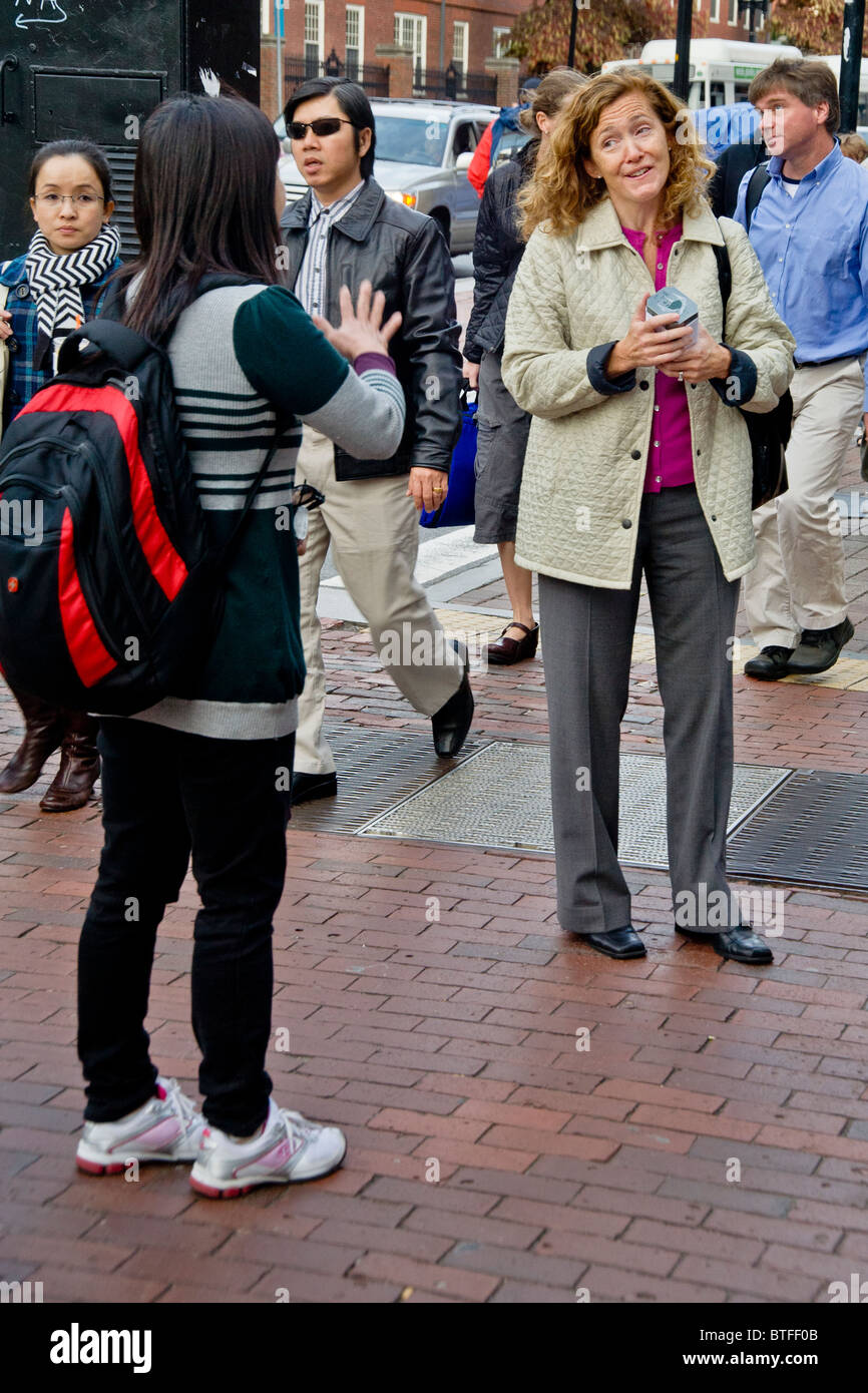 Zwei Frauen haben eine temperamentvolle Unterhaltung an der Massachusetts Avenue in Harvard Square, Cambridge, MA. Beachten Sie asiatische Studenten. Stockfoto