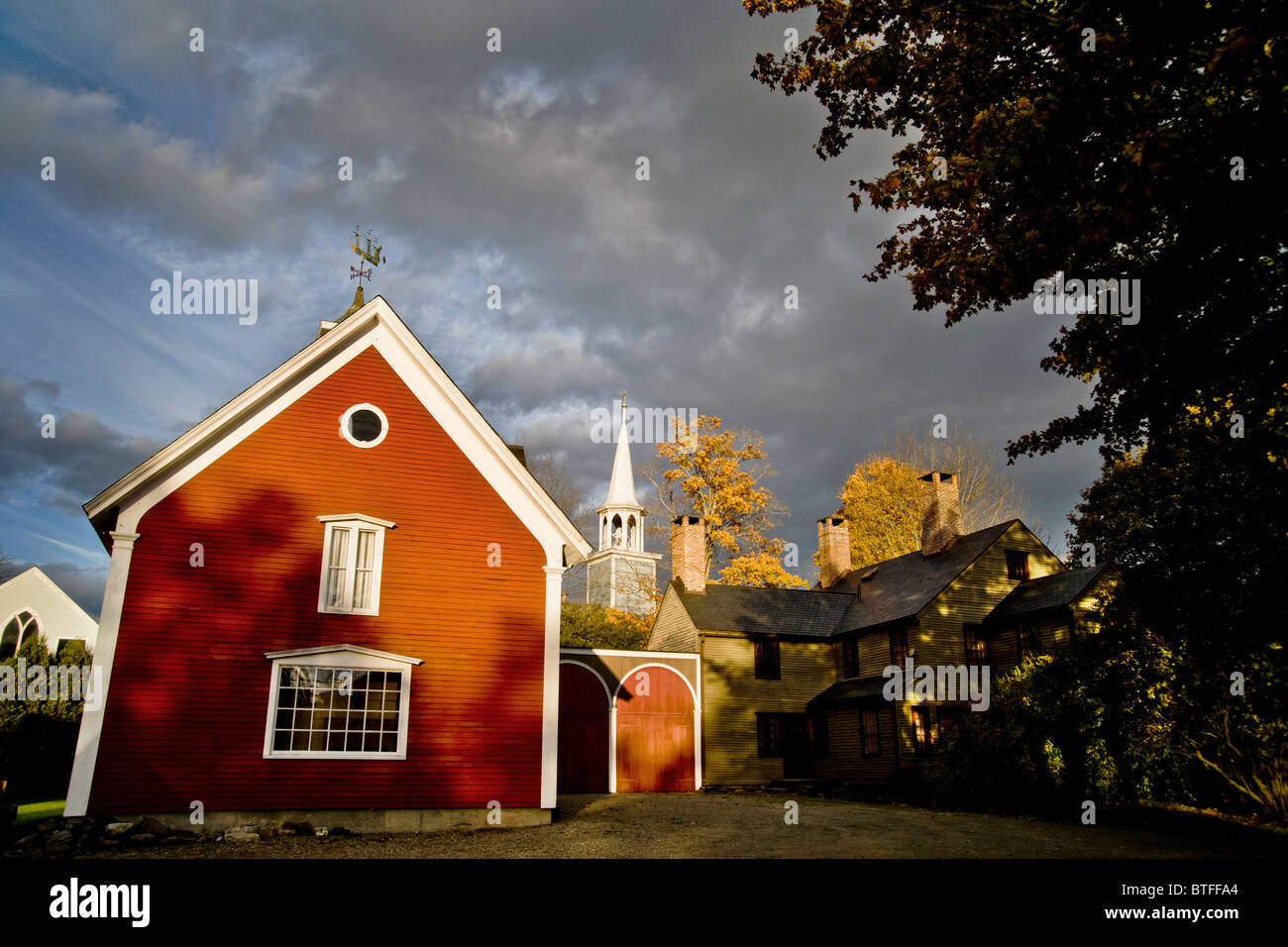 Herbstsonne scheint auf eine rote Scheune und ein Kirchturm-Kirche in Wiscasset, Maine. Stockfoto