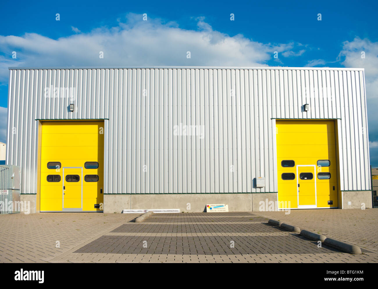 Industriehalle mit zwei identischen gelben Rolltore Stockfoto