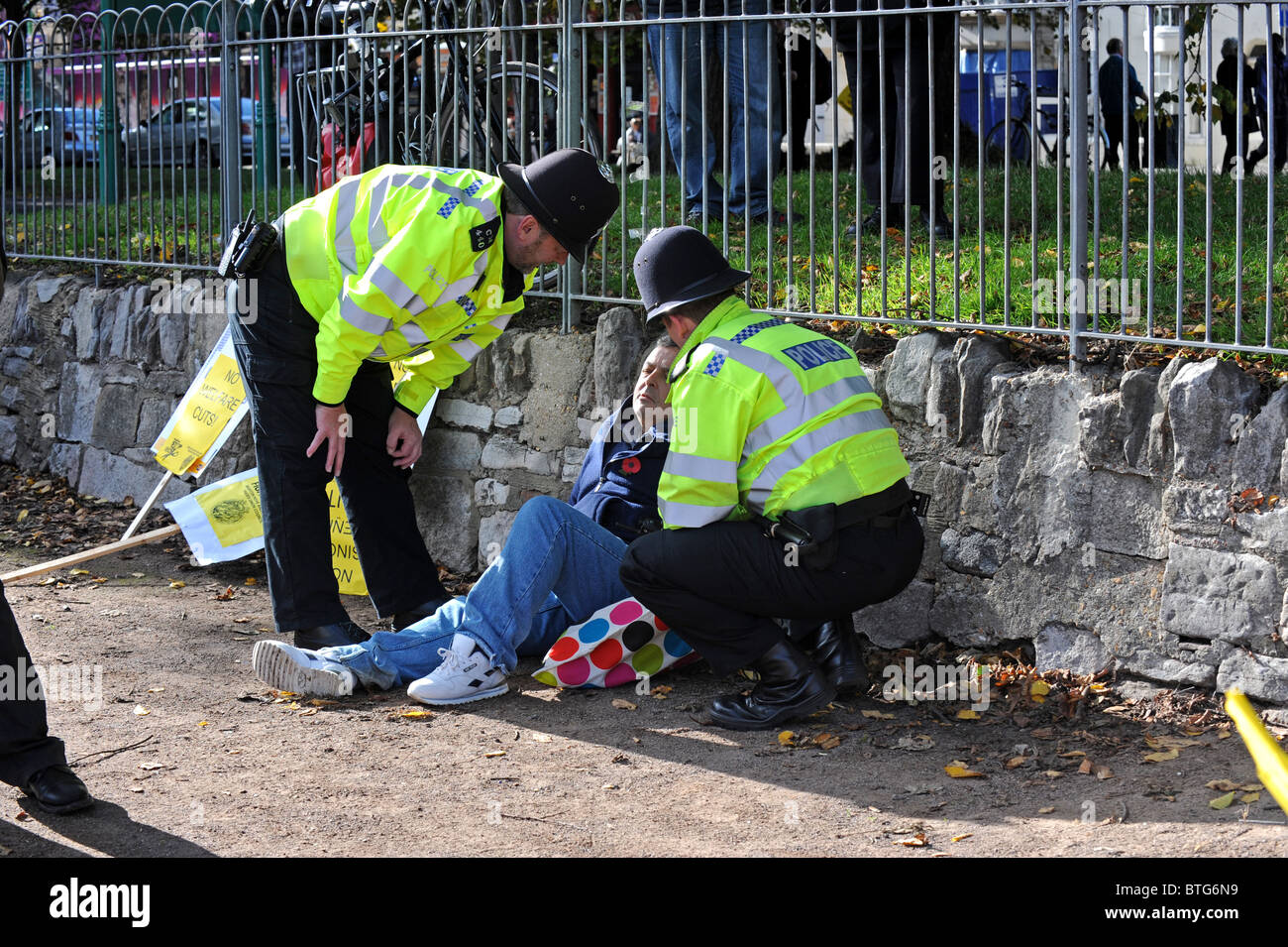 Zwei Polizisten zu tun, mit einem Mann, der vor Beginn der Kürzungen Protestmarsch in Brighton zusammengebrochen Stockfoto