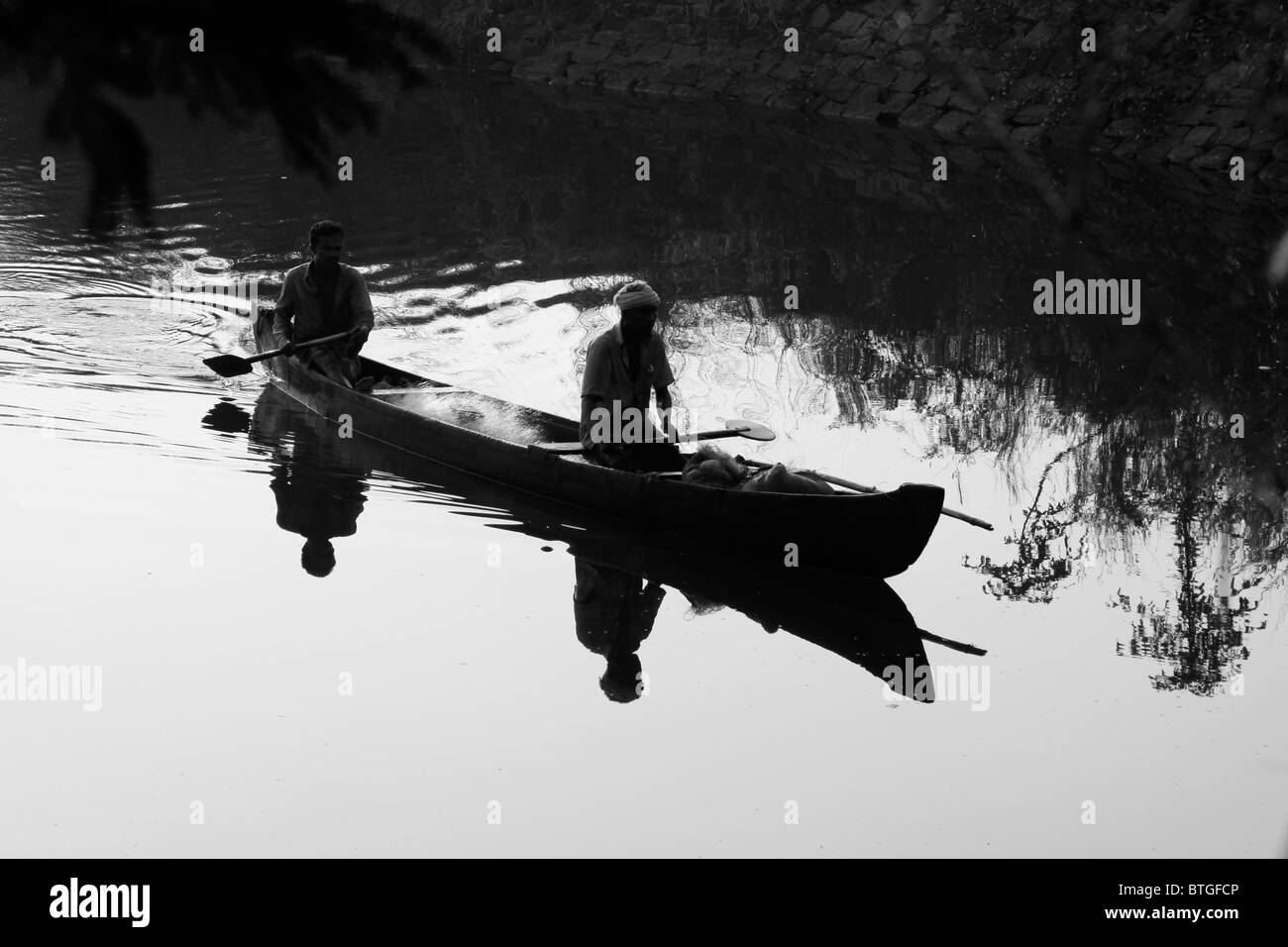 Zwei Fischer genießen eine Abend Boot fahren im stillen, aber schimmernden Fluss. Die Schatten der Bäume zu begleiten. Stockfoto