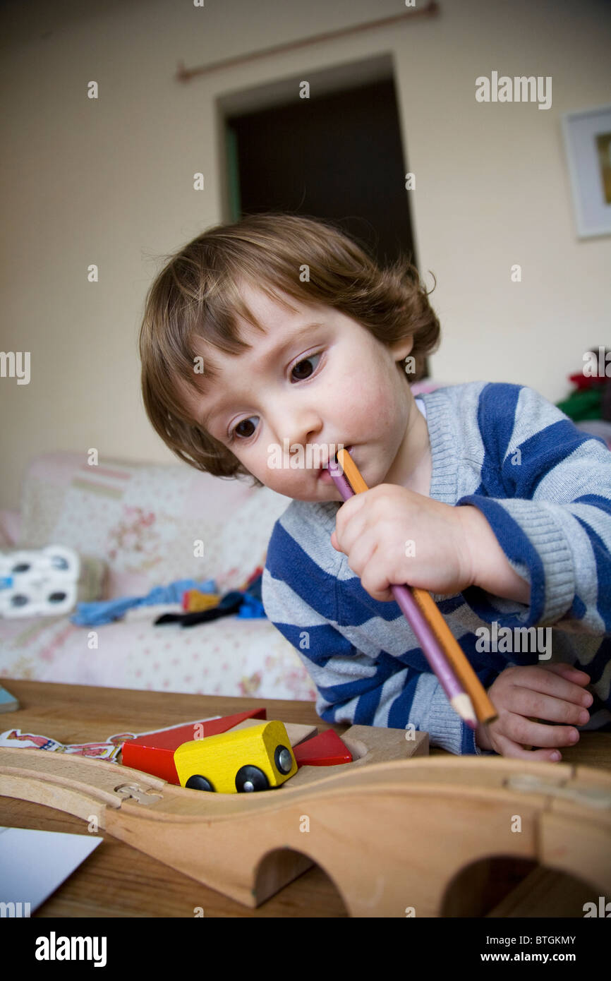 22 Monate alten Jungen spielen mit Farbstiften in den Mund Stockfoto