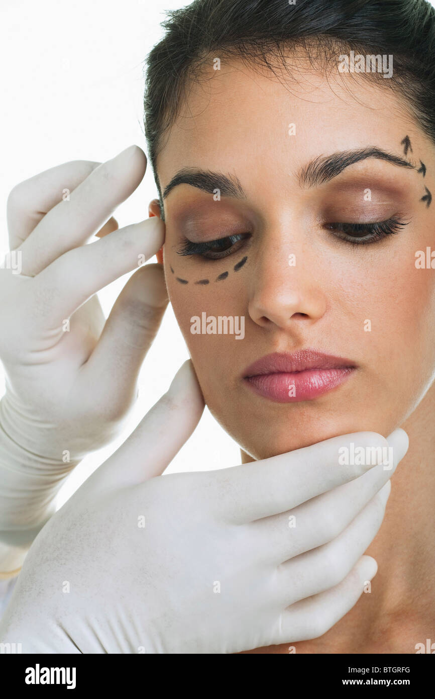 Hände mit OP-Handschuhen auf Gesicht des Patienten mit Distanzmarke Stockfoto