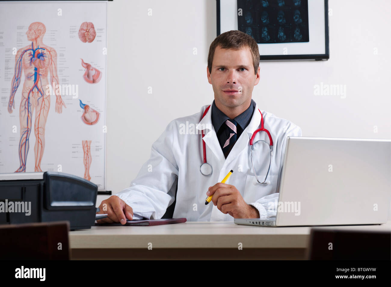 Arzt in seinem Büro mit Herz-Kreislauf-System-Chart und laptop Stockfoto