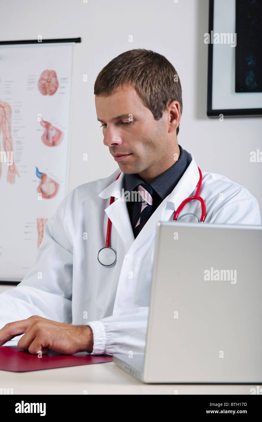 Arzt in seinem Büro mit Herz-Kreislauf-System-Chart und laptop Stockfoto