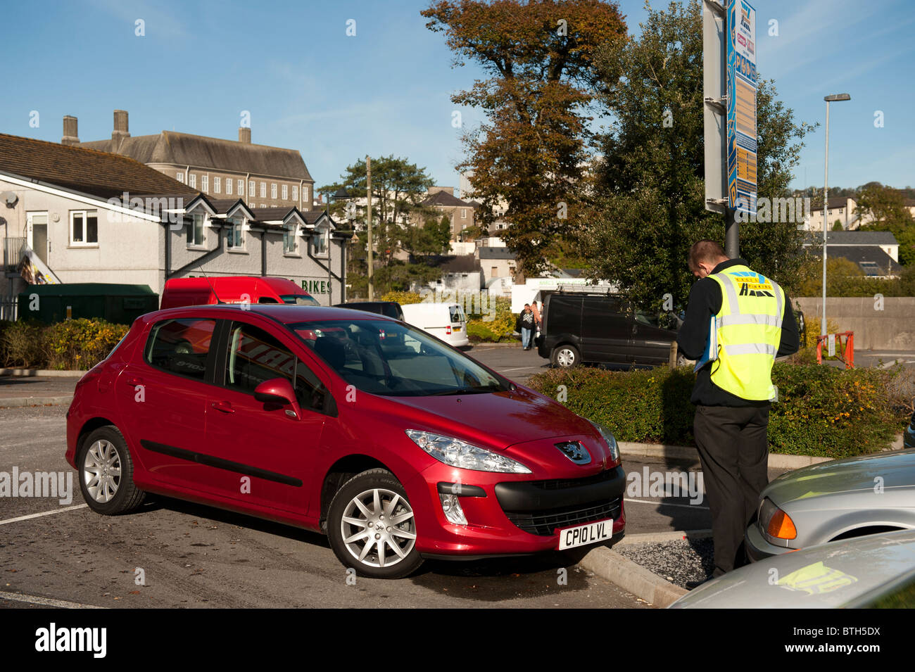 ein privater Parkplatz Attendant rund um ein Ticket zu einem Auto, UK Stockfoto
