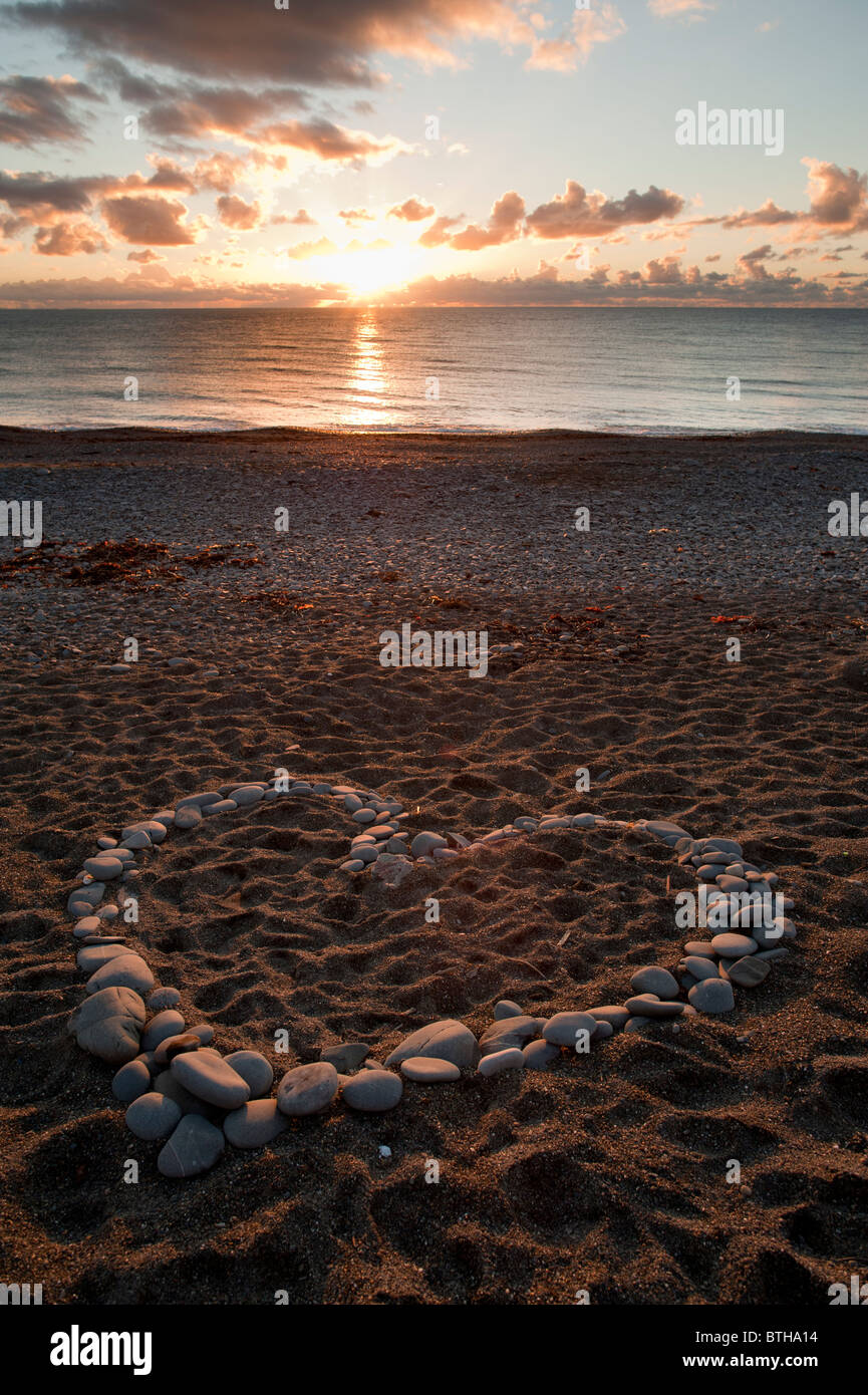 Eine Herzform gemacht Stein Steine Felsen Kiesel bei Sonnenuntergang am Strand-Wales Aberystwyth UK Stockfoto