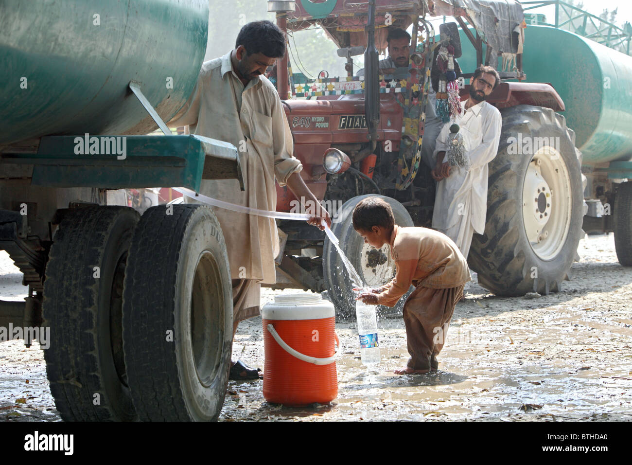 Ein Kind, das Ausfüllen einer Kunststoff-Flasche mit Trinkwasser, Charsadda, Pakistan Stockfoto