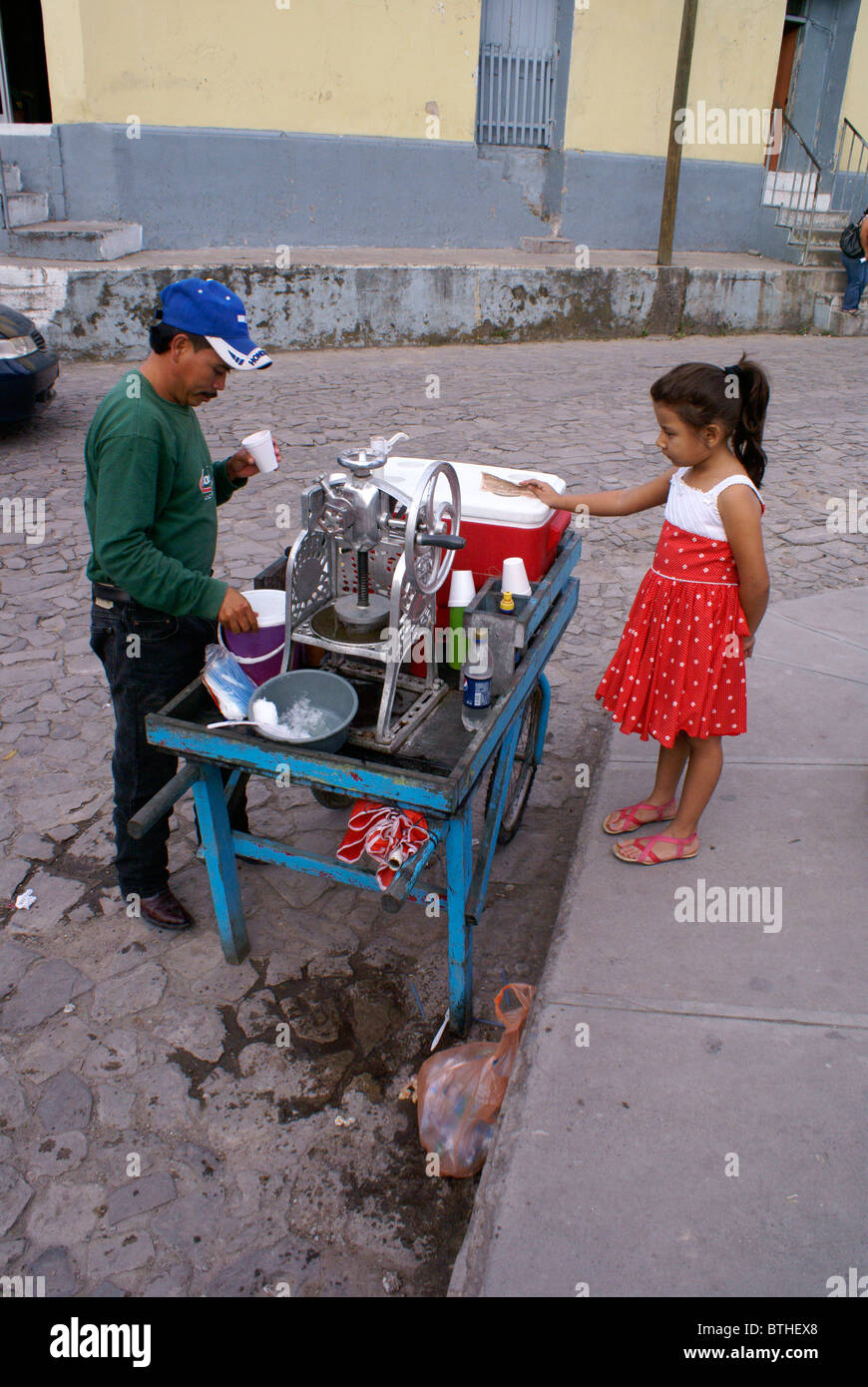 Junge Mädchen von sechs bis zehn Jahren kauft ein Eis von einem Straßenhändler, Santa Rosa de Copán, Honduras Stockfoto