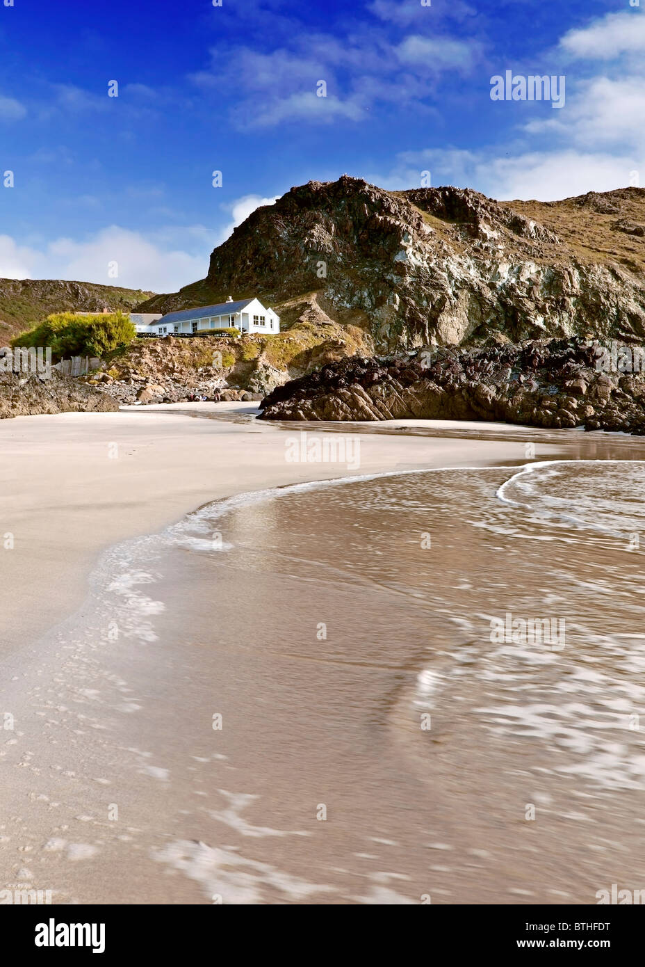 Blick vom Strand und Surfen Sie in Richtung der weißen Café-Hütte auf Kynance Cove Beach, Cornwall Stockfoto