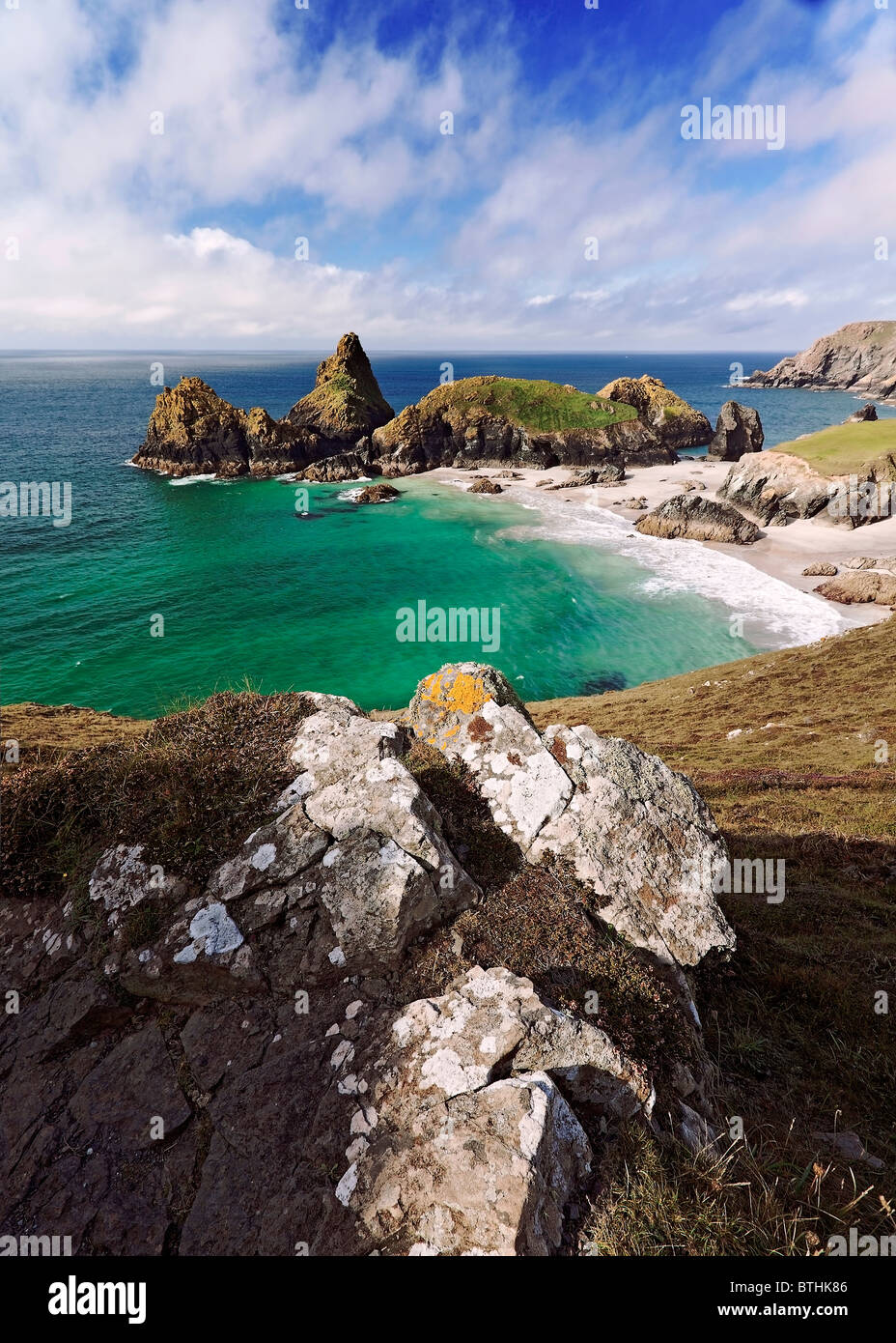 Ein Vordergrund Fels bietet Vordergrund für eine Ansicht über die atemberaubenden Farben der Kynance Cove, The Lizard Halbinsel Cornwall. Stockfoto