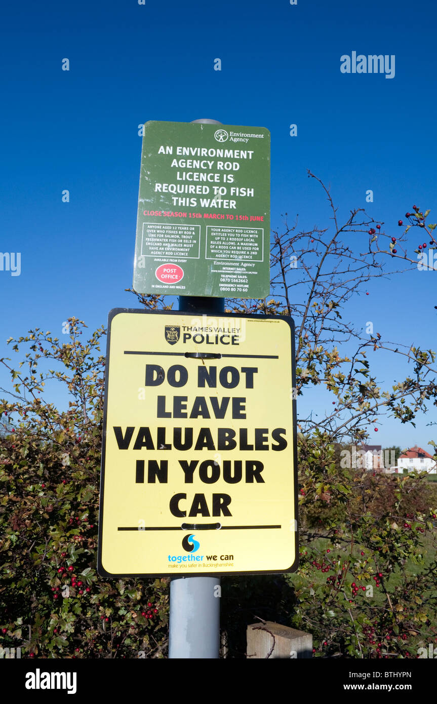 Zwei öffentliche Schilder und Mitteilungen, eine Sicherheit Warnzeichen und Angeln Bekanntmachung über einen Metallpfosten vor einem strahlend blauen Himmel Stockfoto