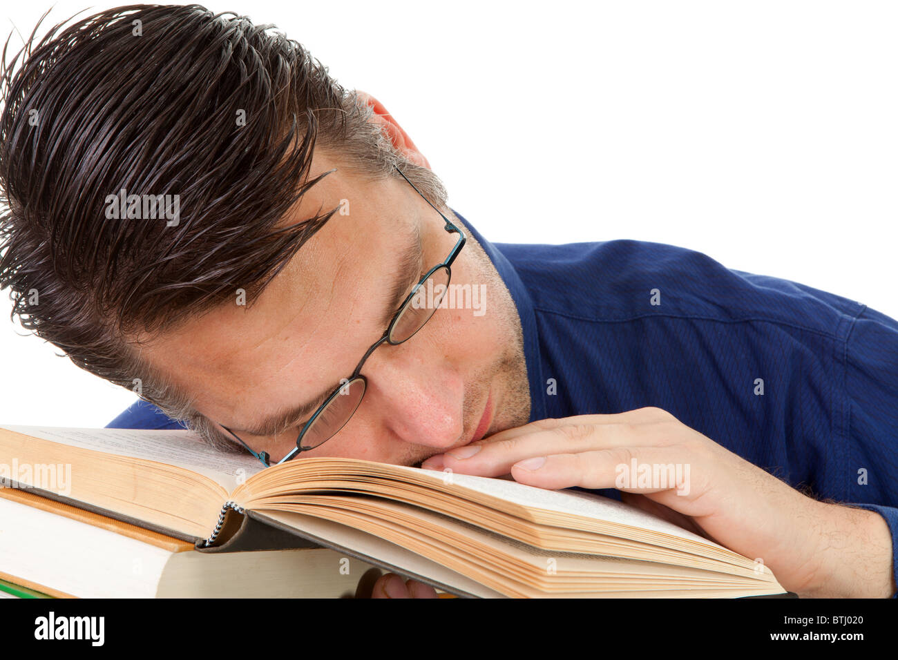 männliche nerdy Geek Einschlafen mit Gesicht auf Stapel Bücher auf weißem Hintergrund Stockfoto