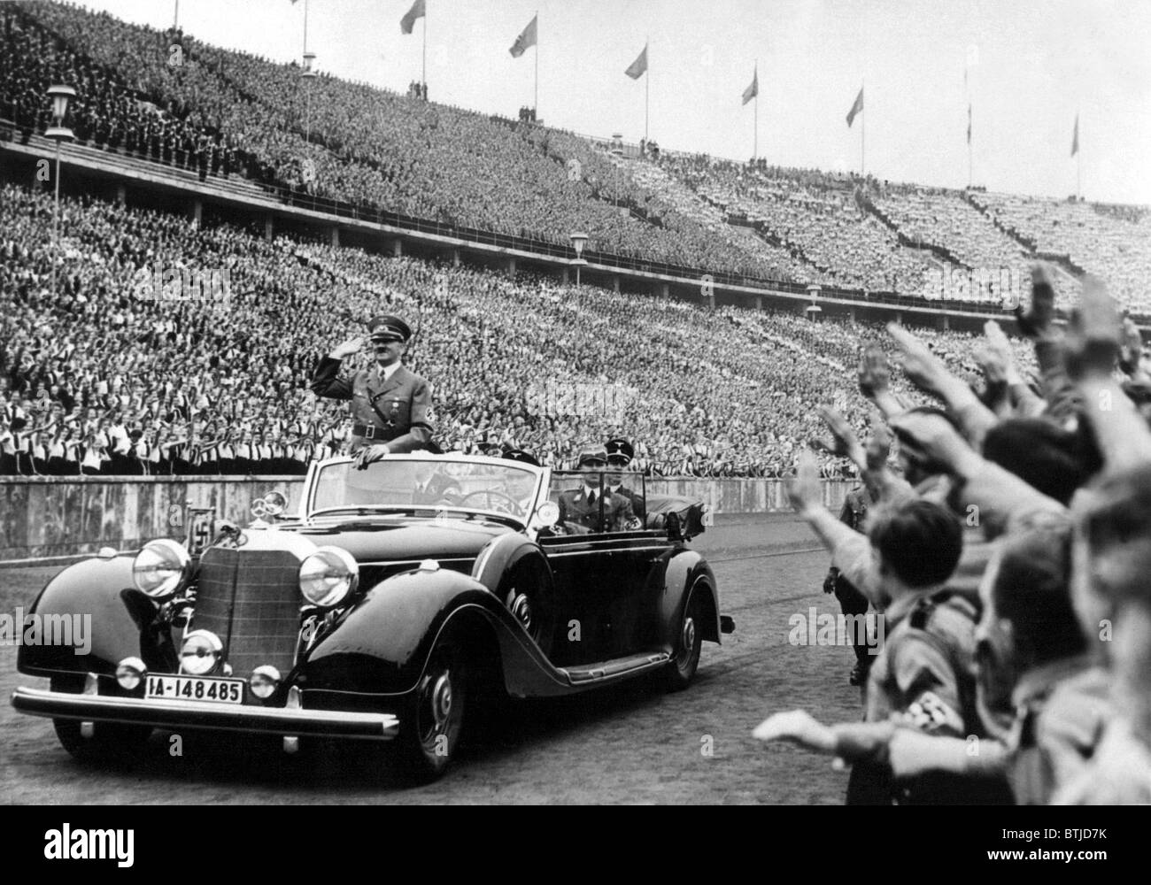 BERLIN--Adolph Hitler (im Auto) begrüßt das riesige, Cherring Publikum im Olympiastadion bei seiner Ankunft eine Maifeiertag Jugend ansprechen Stockfoto