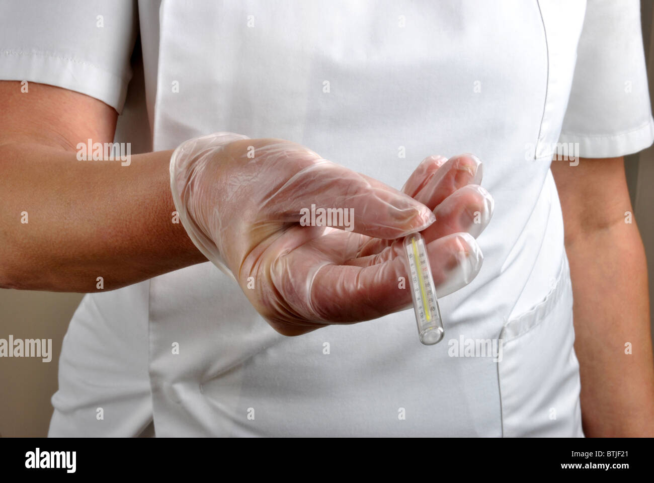 medizinisches Personal mit Einweg-Handschuhe gibt analoge Fieberthermometer Stockfoto