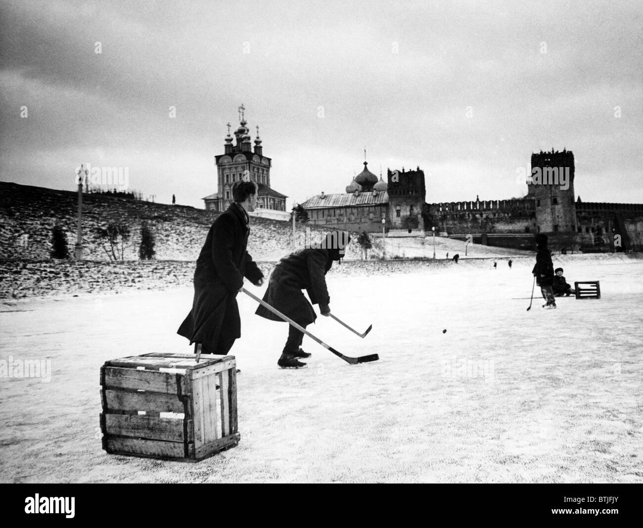 Junge Russen spielt Hockey auf einem zugefrorenen Teich mit dem Novo-Devichie-Kloster im Hintergrund, Moskau, 1962. Stockfoto