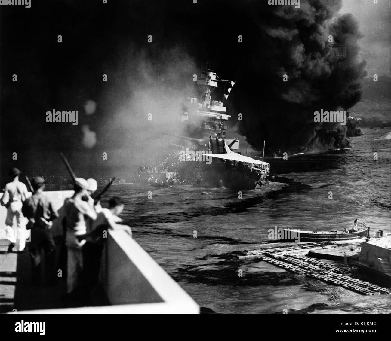 Pearl Harbor: Angeschlagen durch Fliegerbomben und Torpedos, der USS California wird evakuiert, als Matrosen und Soldaten blicken auf, 7. Dezember 1941 Stockfoto