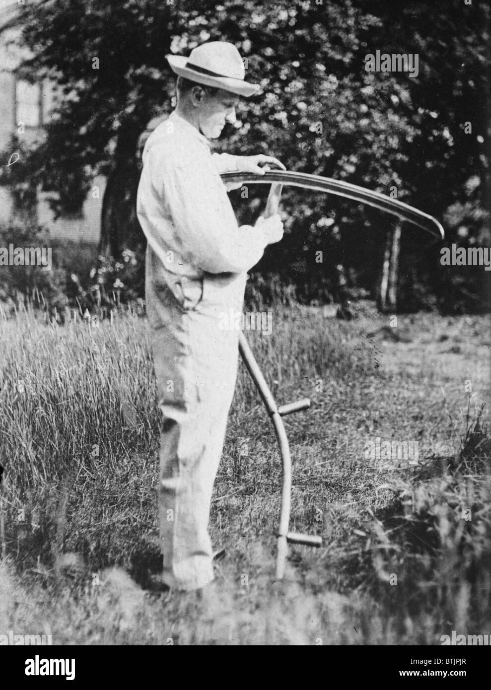 Präsident Calvin Coolidge (1872-33) schärfen einer Sense auf seiner Farm in Vermont. Stockfoto