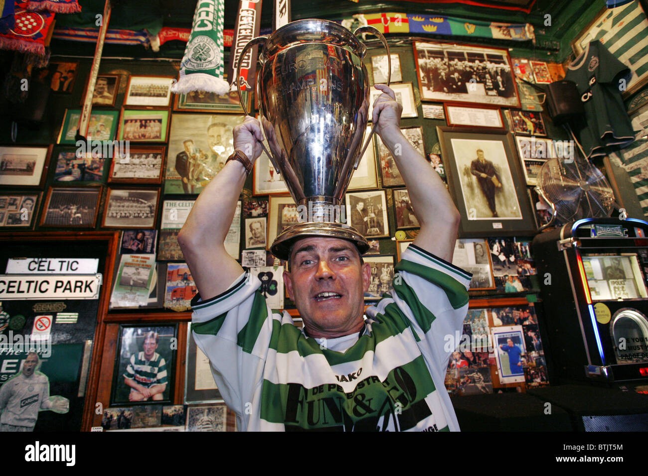 Keltische Lüfter mit einer Kopie der 1967 European Cup Trophy, Bairds Bar aka "The Celtic Pub", Glasgow, Schottland Stockfoto