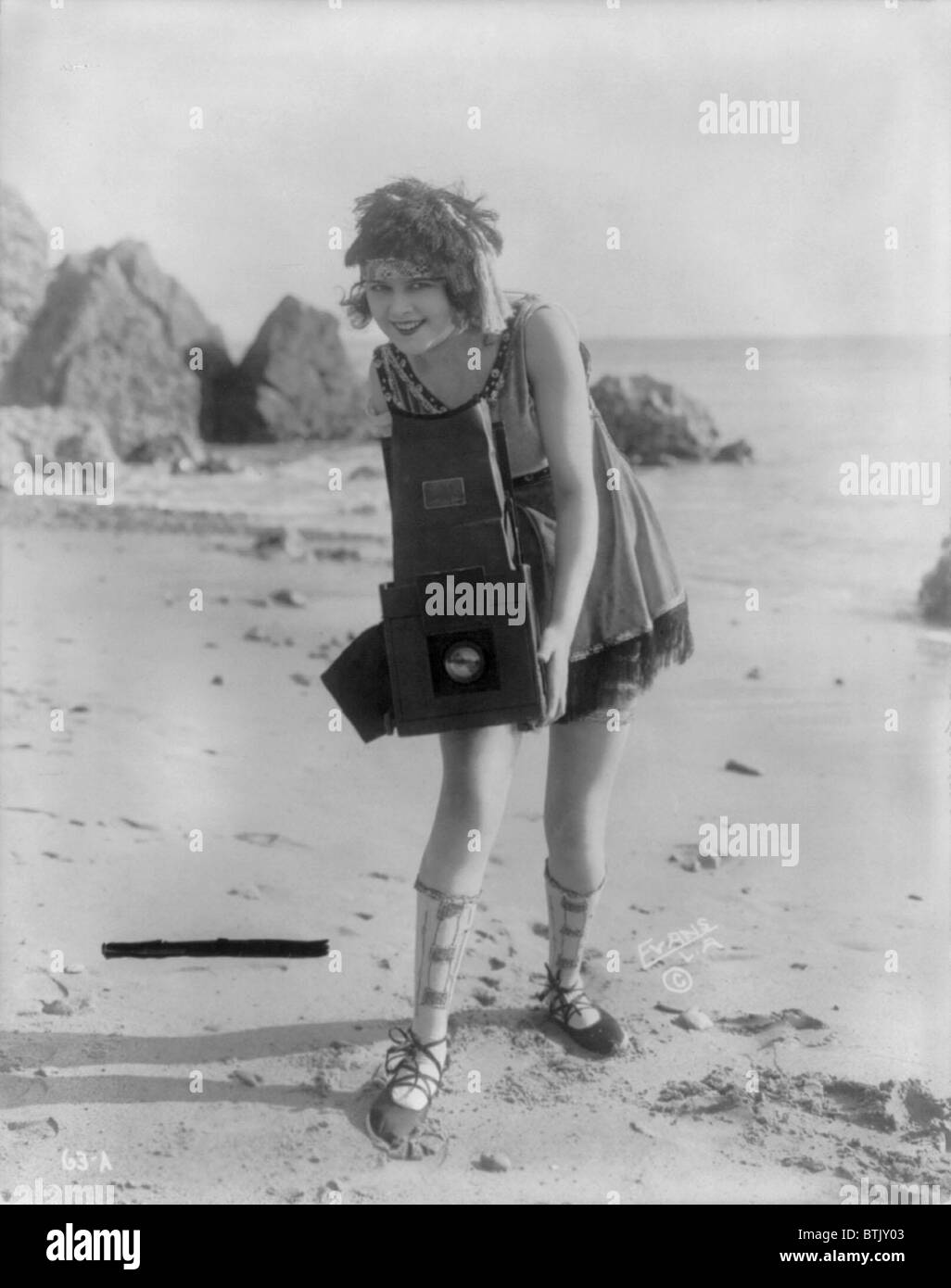 Myrte Lind, eine junge Frau posiert mit einem Graflex Kamera am Strand, 1919. Stockfoto