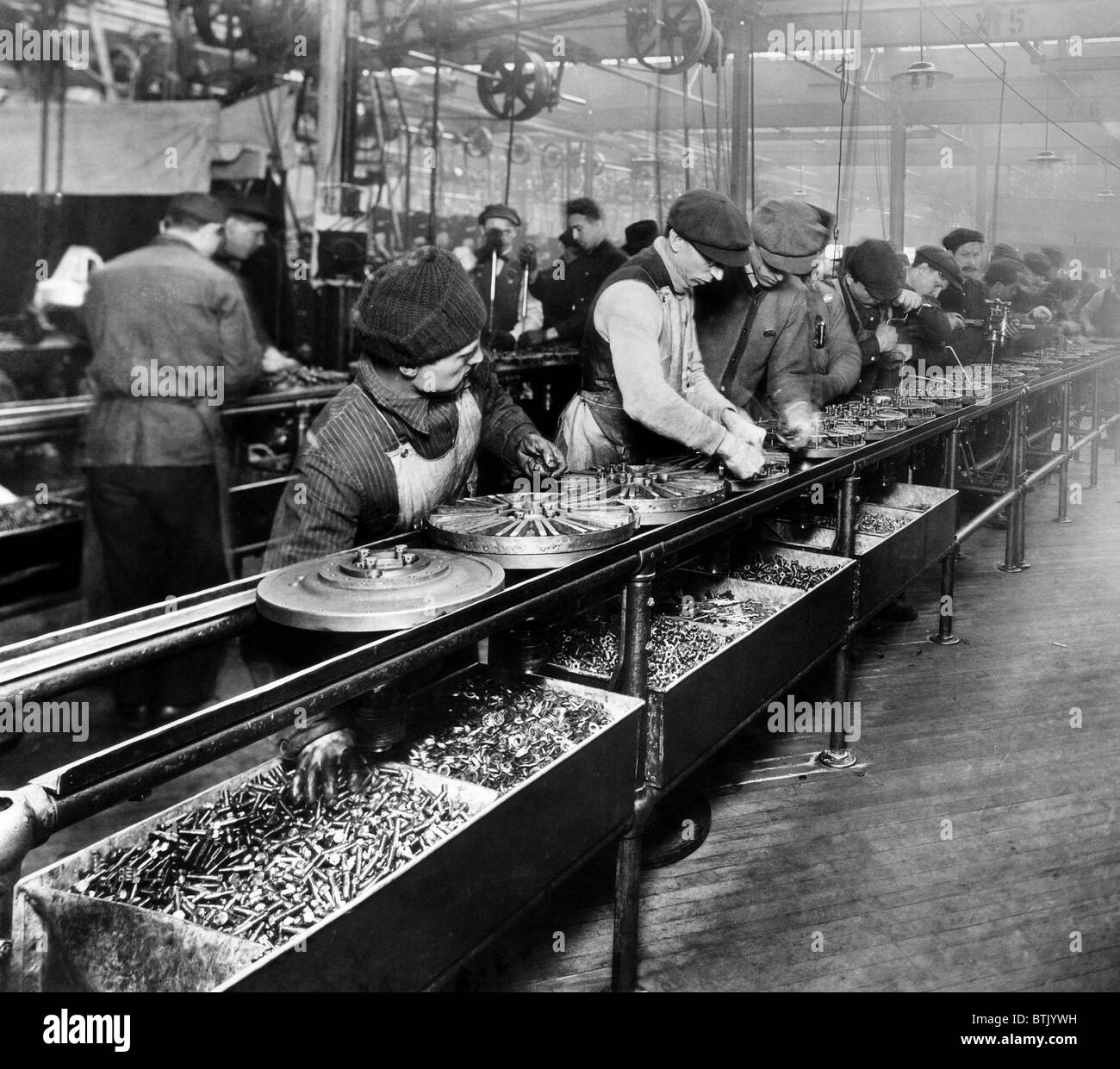 Männer arbeiten an den Schwungrad Magnetzünder, der erste hergestellte Teil auf einer beweglichen Montagelinie, Ford Motor Company-Werk in gebaut werden Stockfoto