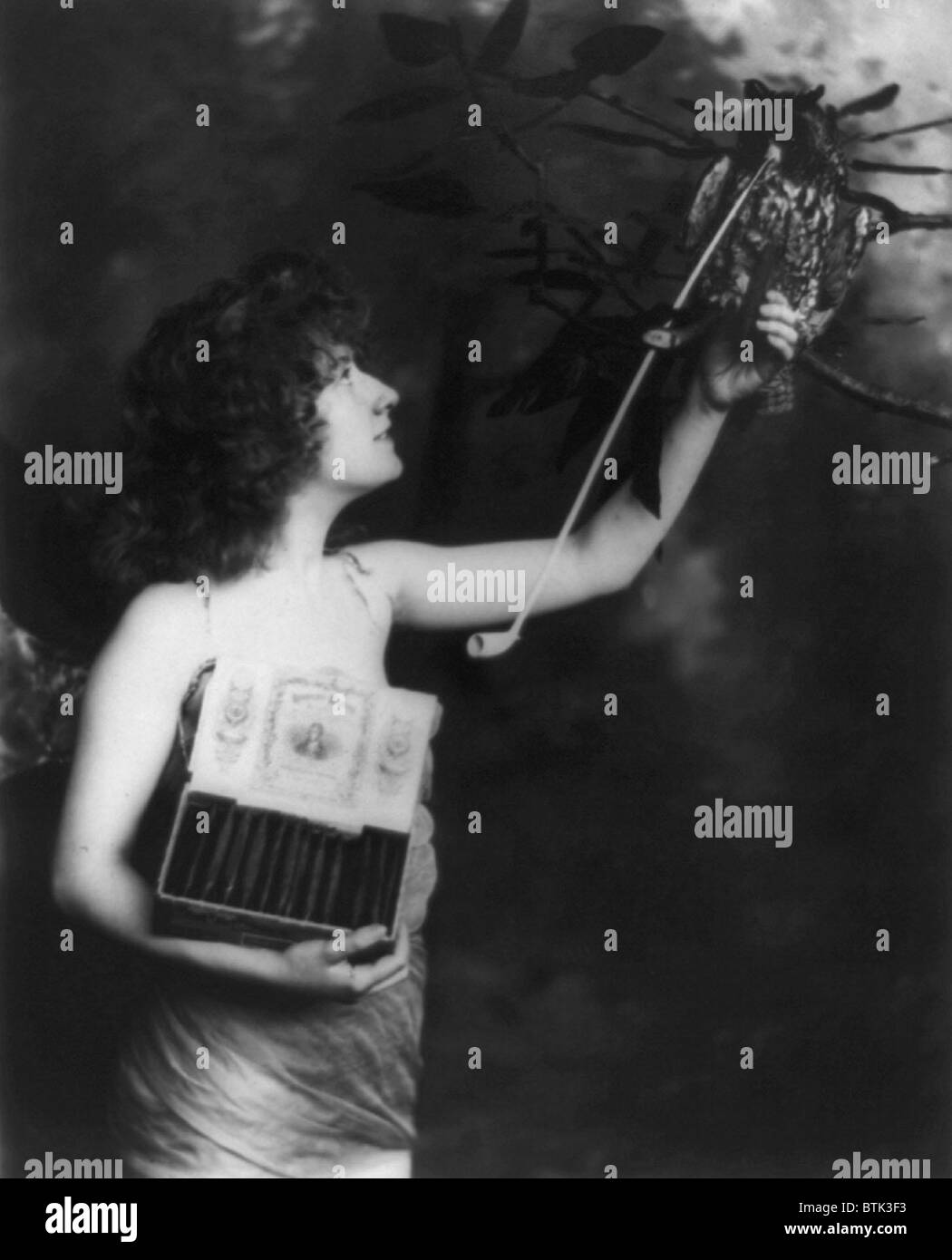 Frau trägt eine geflügelte Kostüm und hält Kasten Robert Burns Zigarren bietet eine Zigarre, einer ausgestopften Eule mit lange Pfeife im Munde, Originaltitel: "Habe eine", fotografieren, 1900 Stockfoto