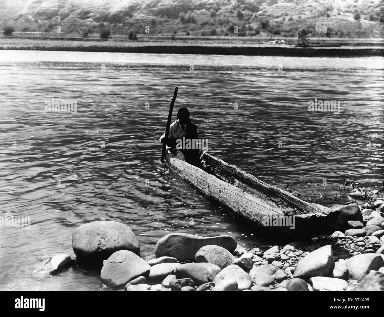 Nez Percé Kanu. Nez Percé Mann mit Pol Einbaum zum felsigen Ufer manövrieren. Curtis, ca. 1910 Stockfoto