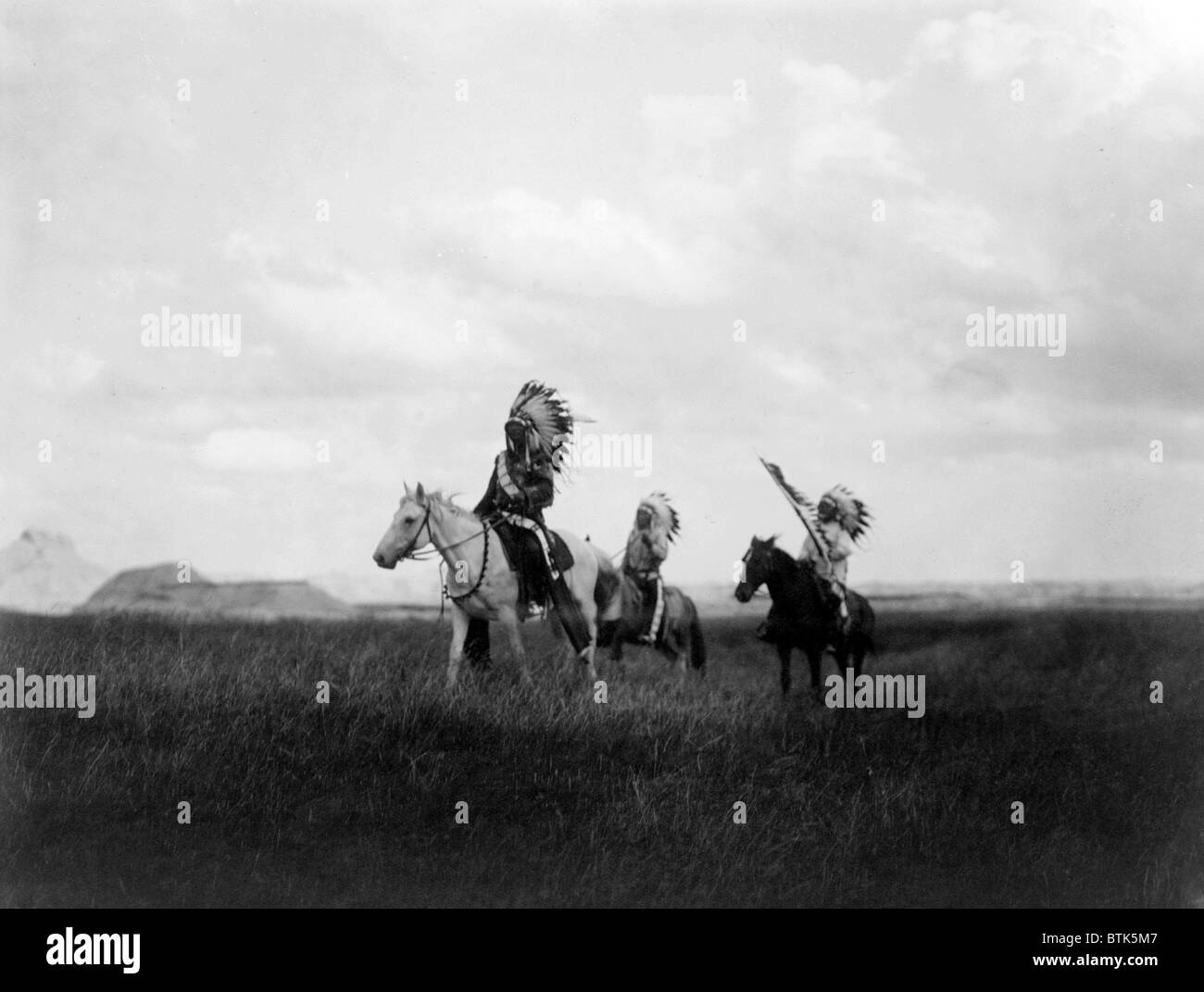 Der Marsch der Sioux, drei Sioux-Indianer zu Pferd auf Ebenen mit Felsformationen im Hintergrund, Foto von Curtis, 1905 Stockfoto