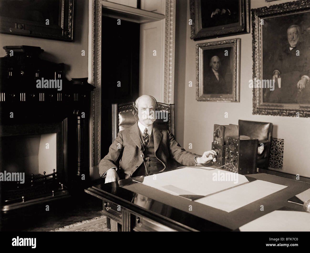 Charles Evans Hughes (1862 – 1948), Staatssekretär während der Harding-Administration, eine frühe Radiohören in seinem Büro. 1922. Stockfoto